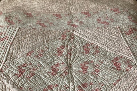 Cream patchwork quilt with scattered pink flowers