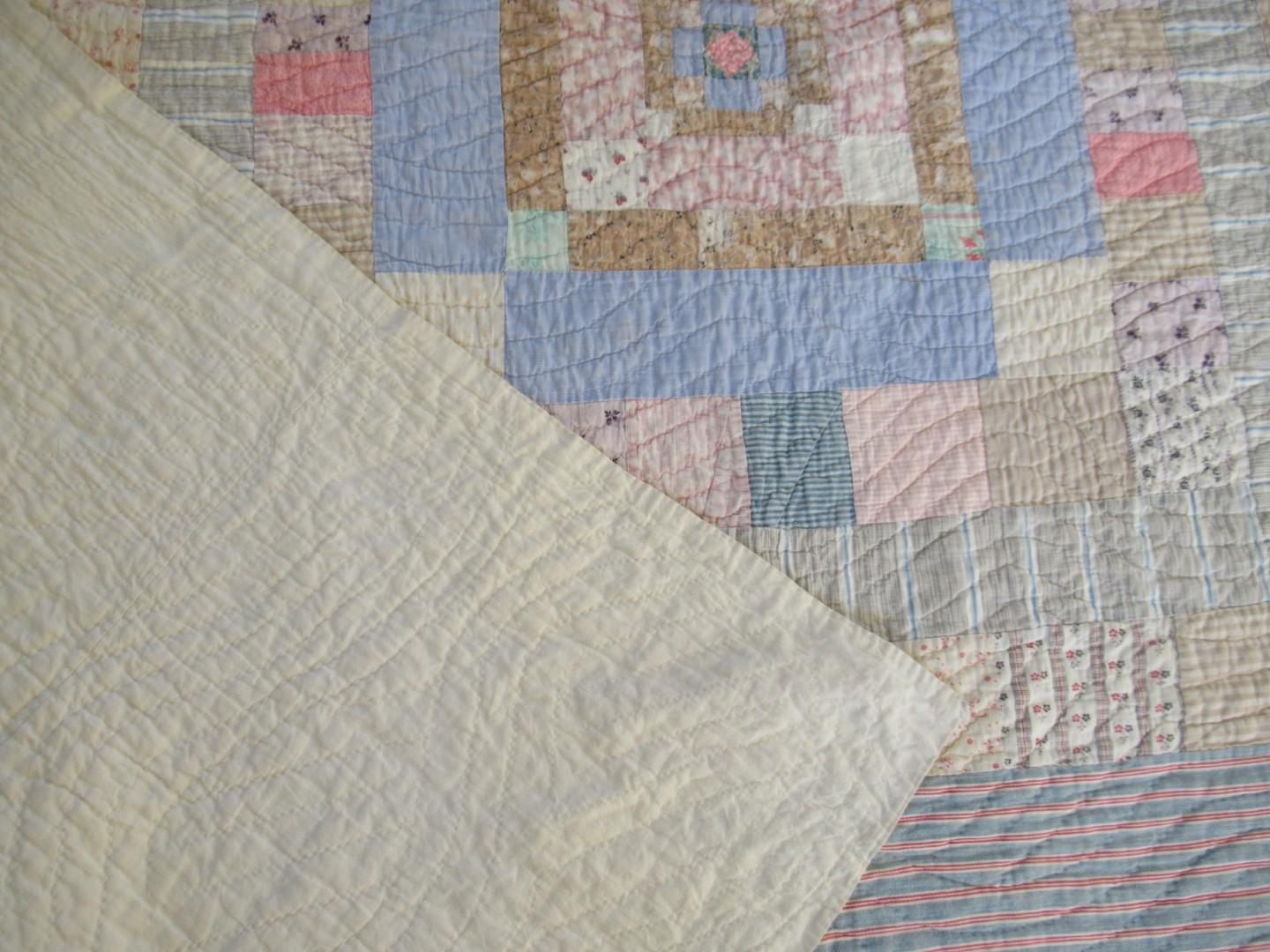 Patchwork quilt in blues and beiges with off white backing corner turned over