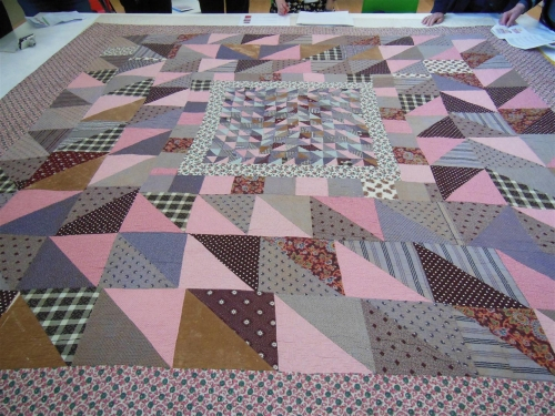 Patchwork quilt in blues, pinks and greys of various size triangles