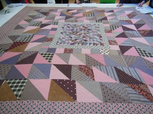 Patchwork quilt in blues, pinks and greys of various size triangles