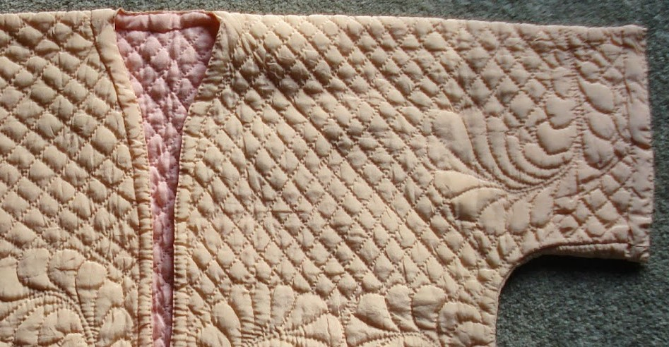 Close-up of Ivory bedjacket with swirling feather designs on a diagonal grid background