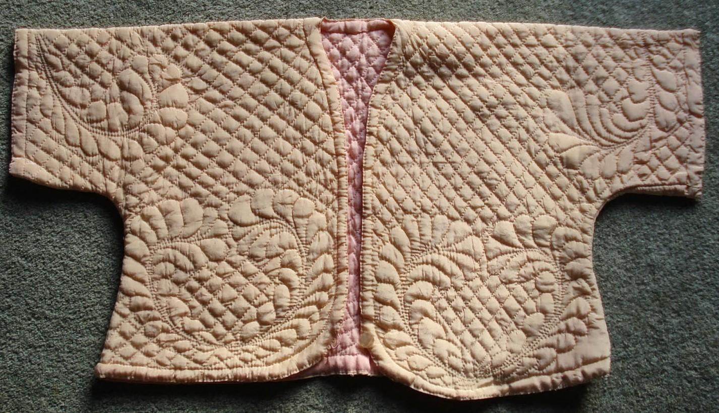 Ivory bedjacket with swirling feather designs on a diagonal grid background