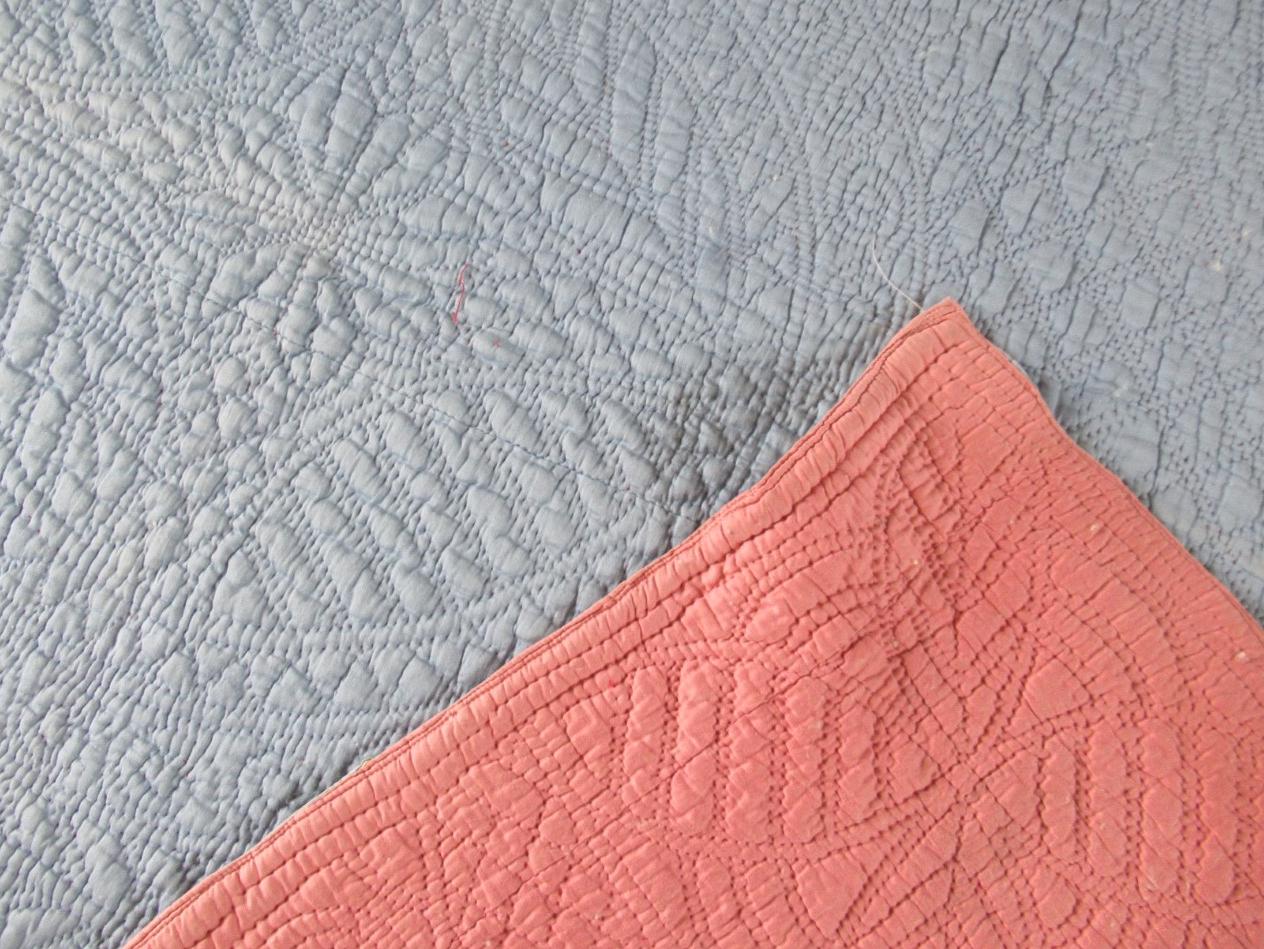Blue grey quilt with pink corner turned over
