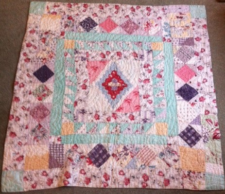 Multi coloured patchwork cot quilt