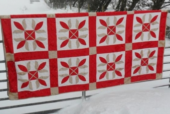 Red white and beige applique quilt hanging on fence