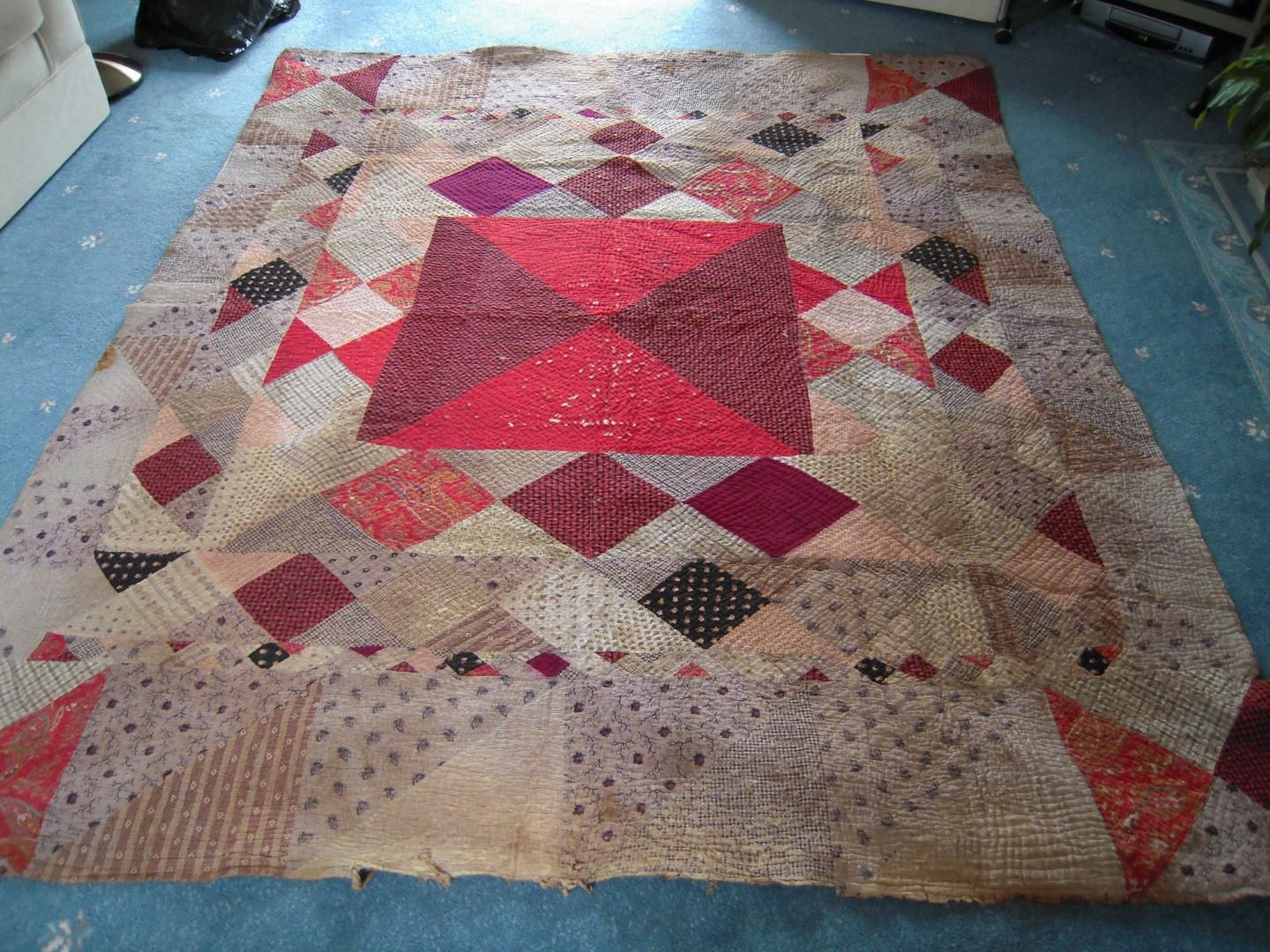 Large geometric patchwork quilt in reds, creams and mauves
