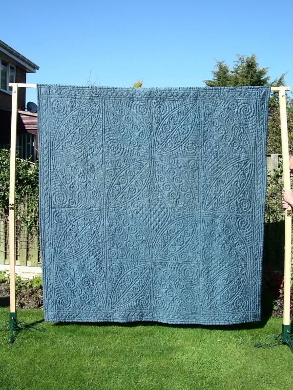 Blue quilt with stitched patterns hanging in garden