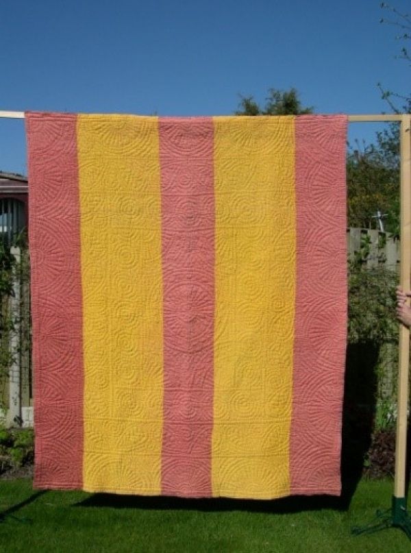 Yellow and Orange Strippy quilt hanging in garden