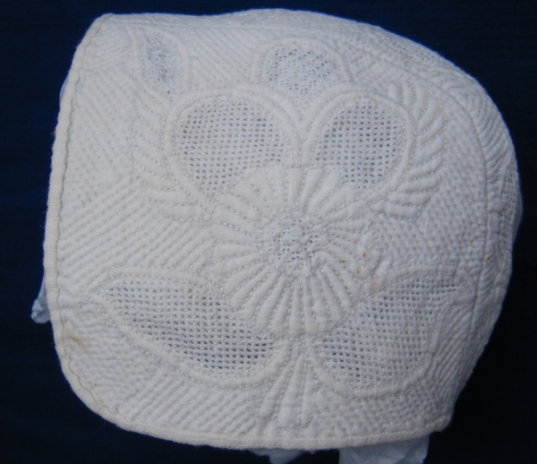 White baby's bonnet with detailed stitching