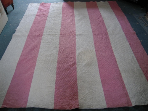 Pink and white strippy quilt laying on floor