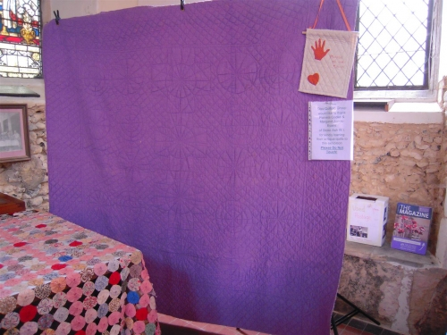 Mauve quilt hanging in front of window