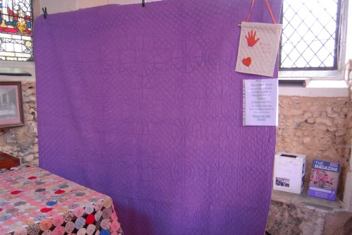 Mauve quilt hanging in front of window