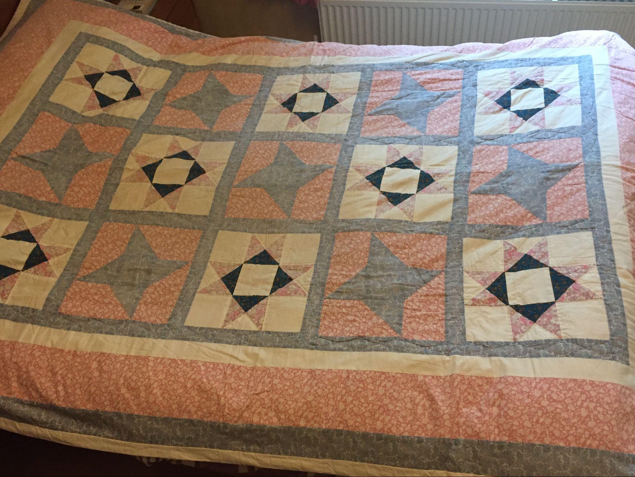 Quilt on bed in pinks and greys