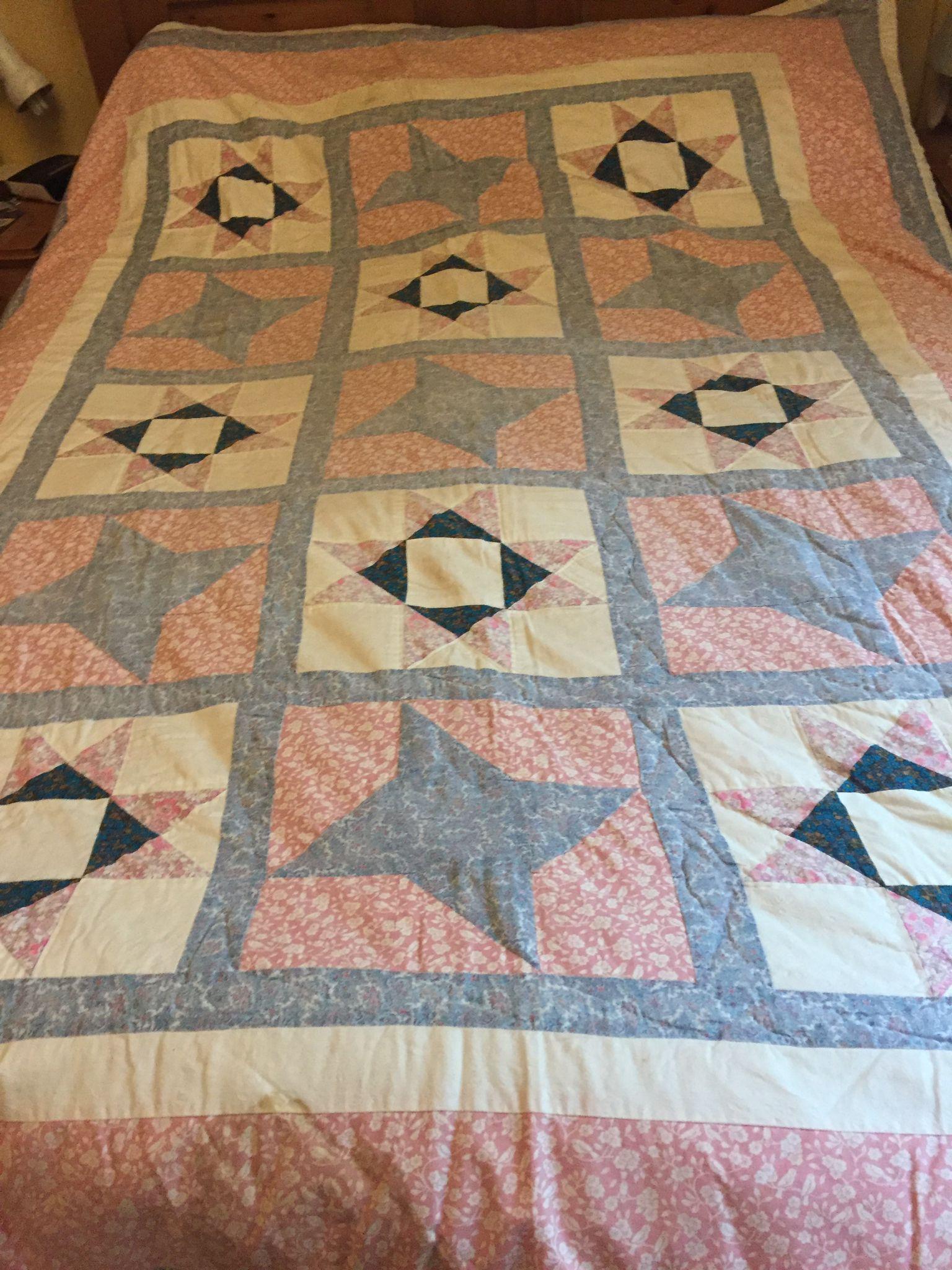 Star block patchwork quilt in greys, pinks and white.