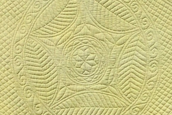 Pale yellow quilt with stitched patterns