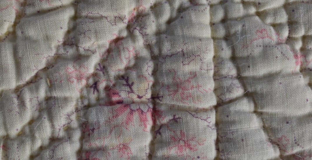 Delicate pink on cream print fabric on back of quilt