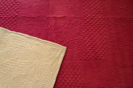 Red stitched quilt with cream corner turned over