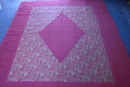 Pink quilt with diamond centre and patterned surround