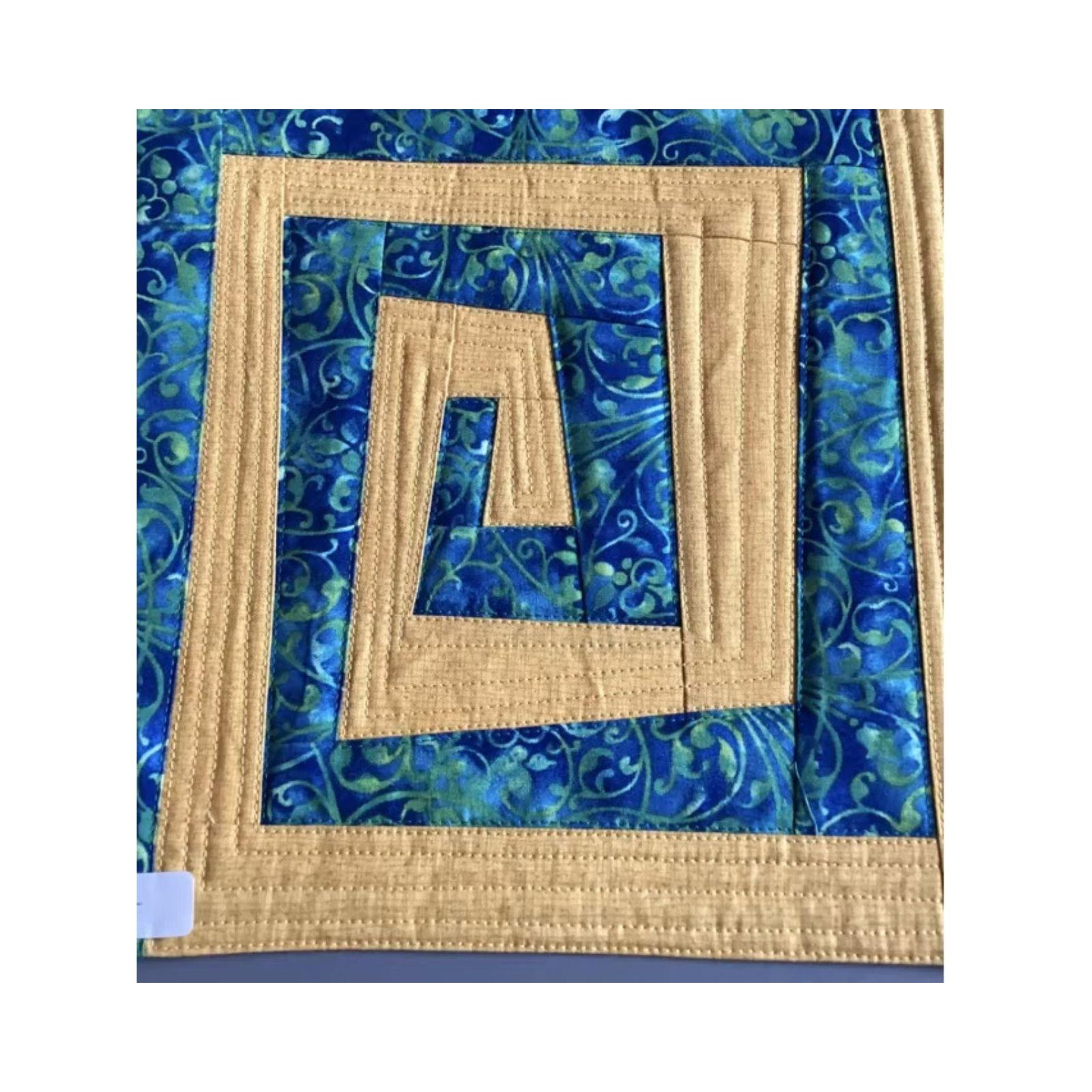 A square quilt with a blue and yellow color scheme. The quilt features a nested square design, with each square getting smaller as it moves towards the center. The blue fabric has a swirling, floral pattern. The background is quilted with straight lines.