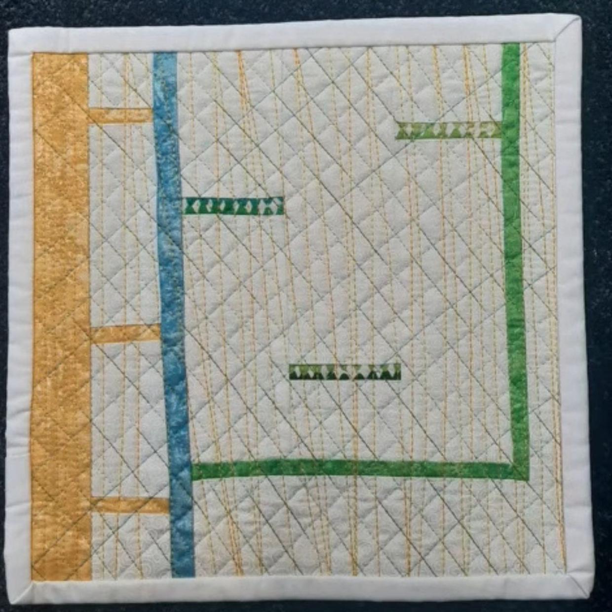 A square quilt with a white background. The quilt features a colorful, abstract design with intersecting lines in shades of green, blue, and yellow. The lines create a sense of movement and dynamism. The background is quilted with a linear pattern.