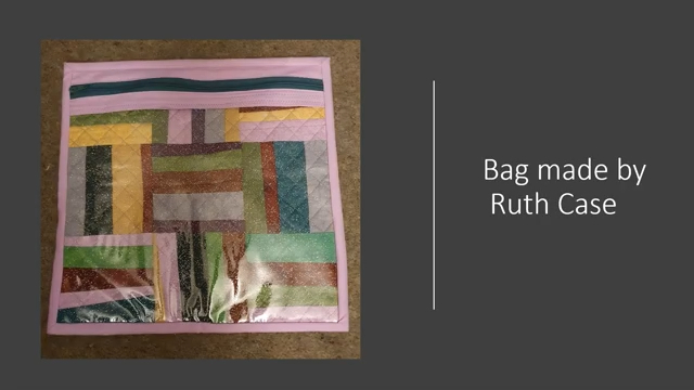 A pink, quilted bag with a clear plastic panel on the front. The bag has a zipper closure and features a colorful patchwork design on the inside.