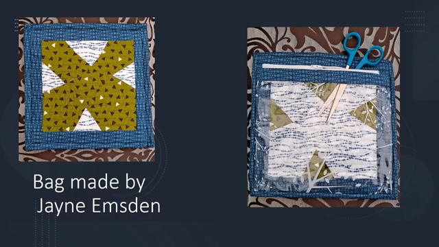 A quilted bag with a blue background and a green cross-shaped design on the front. The inside of the bag contains a clear zipped plastic pocket with sewing tools inside.