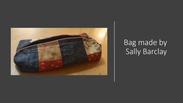 A rectangular, quilted bag with a zipper closure. The bag features a patchwork design with squares in various colours and patterns