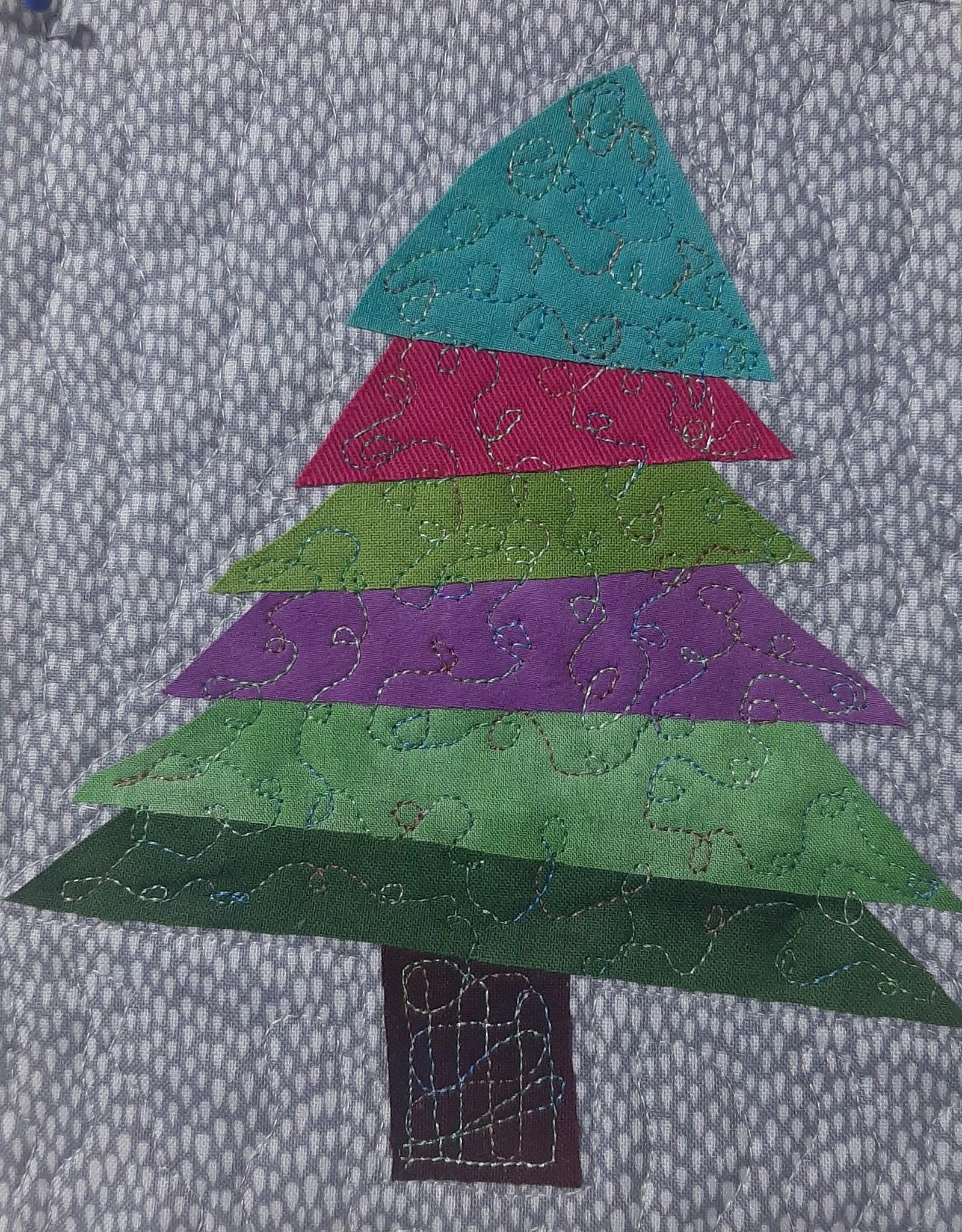 A square quilt with a grey background. The quilt features a colourful Christmas tree made up of triangles in shades of green, purple, pink, and blue. Each triangle has a unique pattern or texture. The background is quilted with a subtle, dotted pattern.