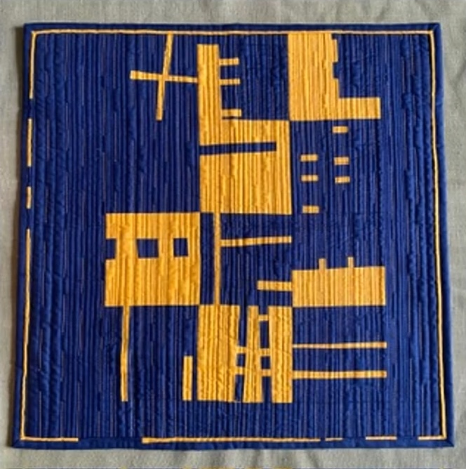 A square quilt with a blue background. The quilt features a geometric design with yellow shapes, including rectangles and squares, arranged in a vertical pattern. The background is quilted with vertical lines. The quilt has a blue border.