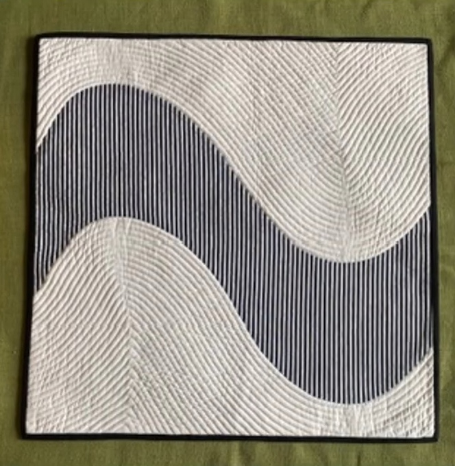A square quilt with a black and white color scheme. The quilt features a dynamic, wavy pattern with curved lines and textured surfaces. The background is quilted with a linear pattern. The quilt has a black border.