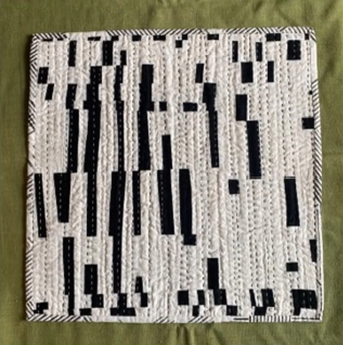 A rectangular quilt with a black and white color scheme. The quilt features a geometric pattern with vertical lines and shapes, creating a sense of movement and rhythm. The background is quilted with a linear pattern. 
