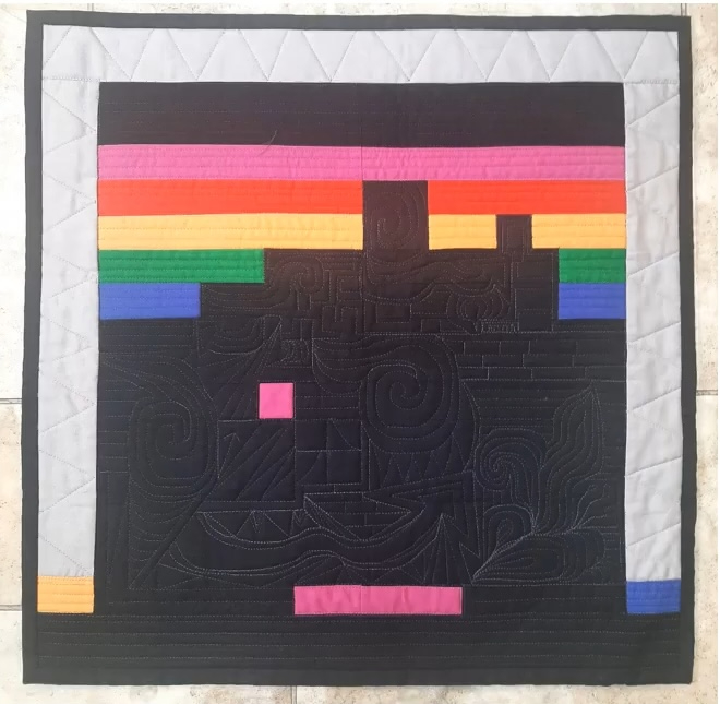 A square quilt with a black background. The quilt features a colorful, geometric design with rectangles and triangles in various colors, including pink, orange, yellow, green, and blue. The shapes are arranged in a horizontal pattern, creating a sense of movement. The background is quilted with a linear pattern. 