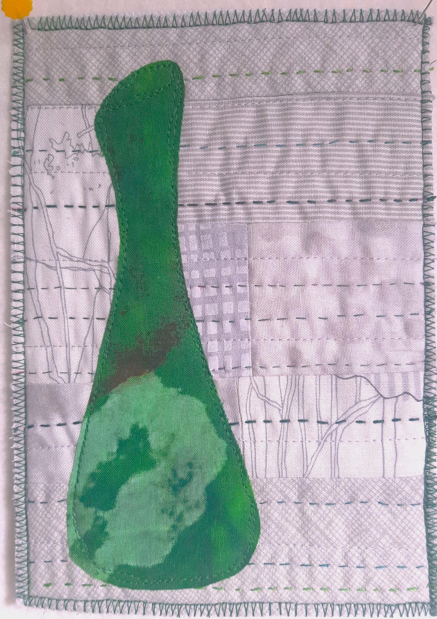 A square quilt with a predominantly grey background. A large, green, vase-like shape dominates the centre. The background fabric has a subtle texture and pattern, possibly representing a landscape or cityscape. The quilt is framed by a green zigzag stitched border.