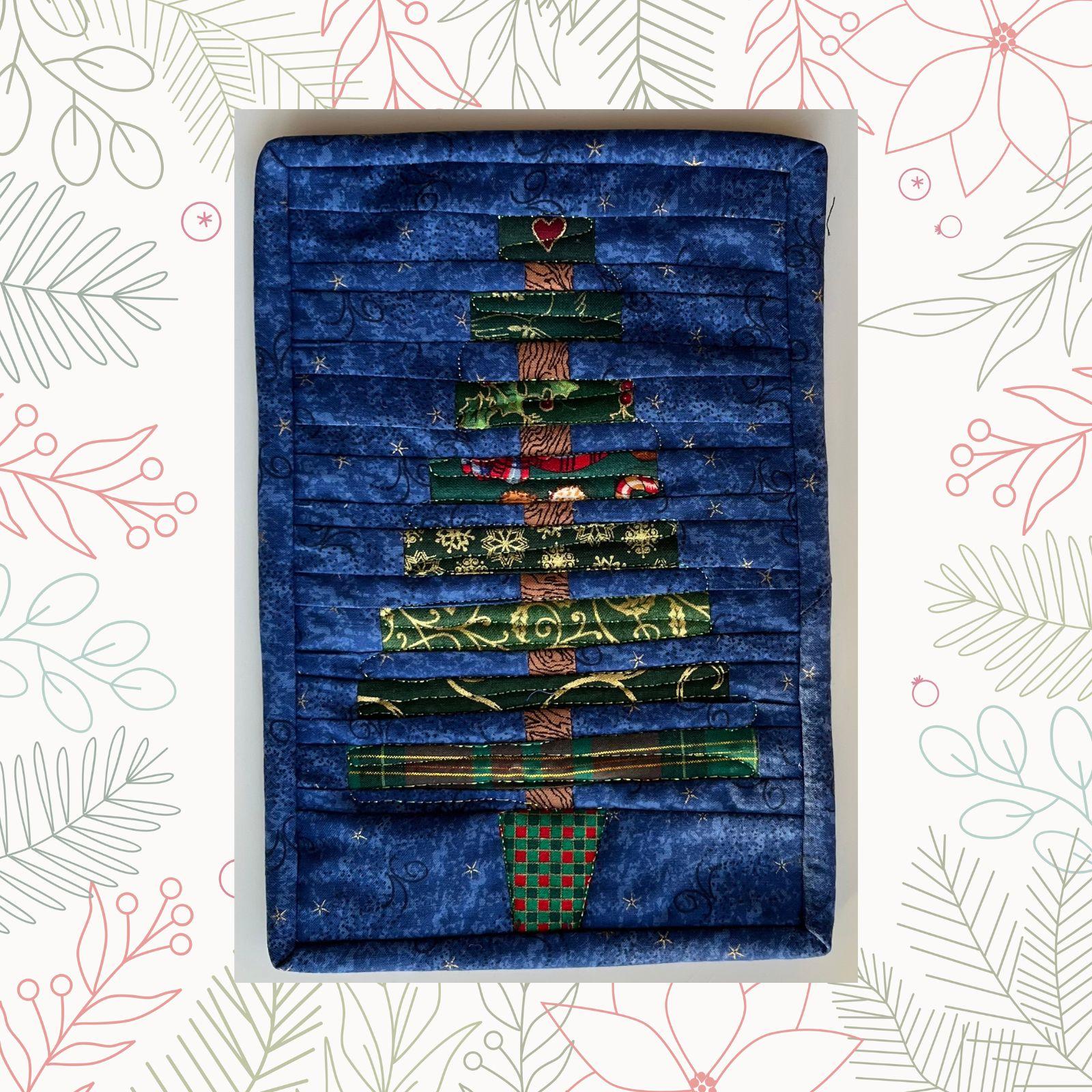 A rectangular quilt with a blue background and a red border. The quilt features a Christmas tree made up of horizontal strips of fabric in various colors and patterns, including green, red, gold, and plaid. The background is quilted with a linear pattern.