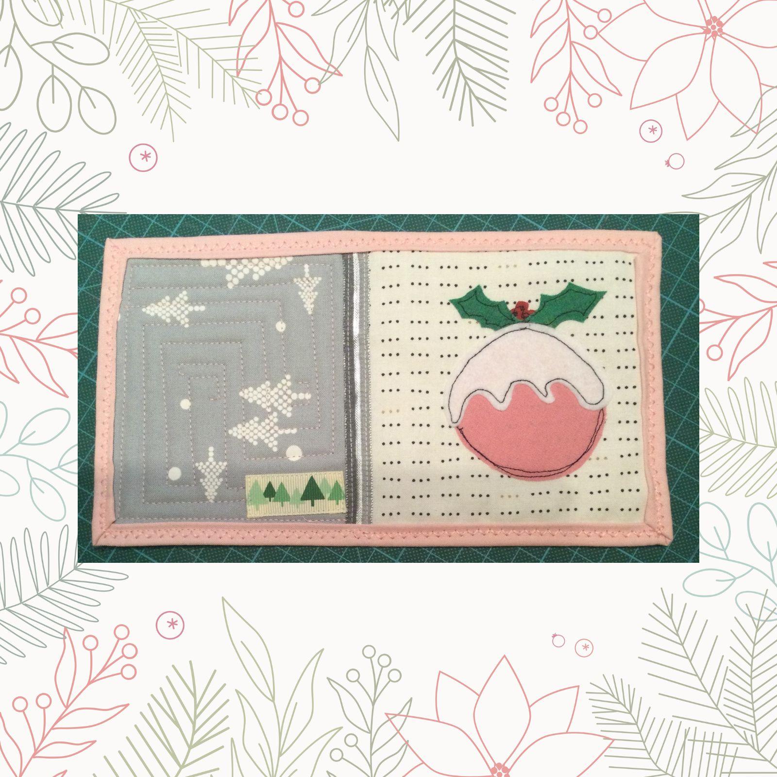 A rectangular quilt with a pink border. The quilt is divided into two sections. The left section has a gray background with a pattern of white trees and snowflakes. The right section has a white background with a pink Christmas pudding decorated with holly leaves. The background is quilted on the left hand side in a rectangular spiral pattern.