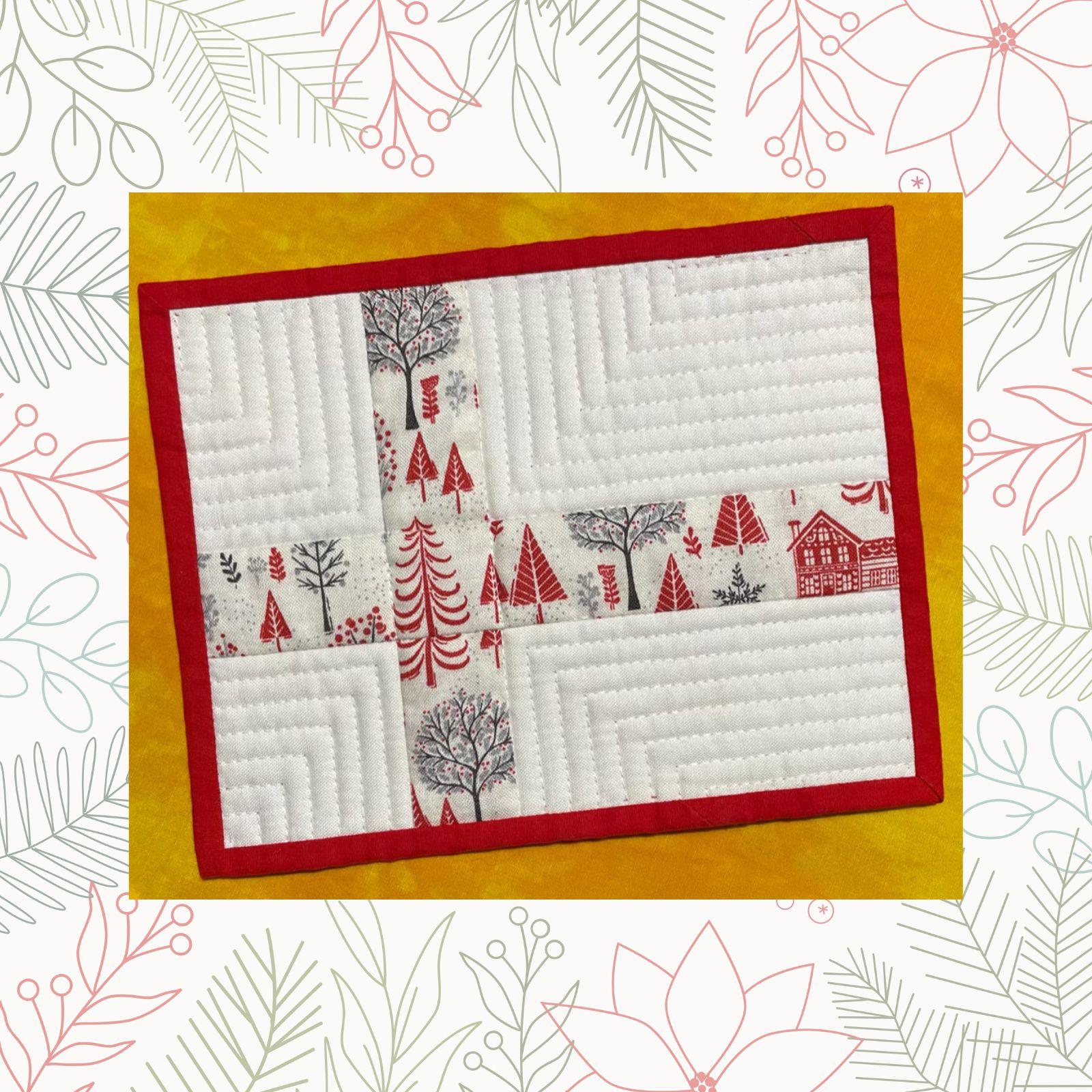 A rectangular quilt with a white background and a red border. The quilt features a winter scene with houses, trees, and snowmen. The background is quilted with a linear pattern.
