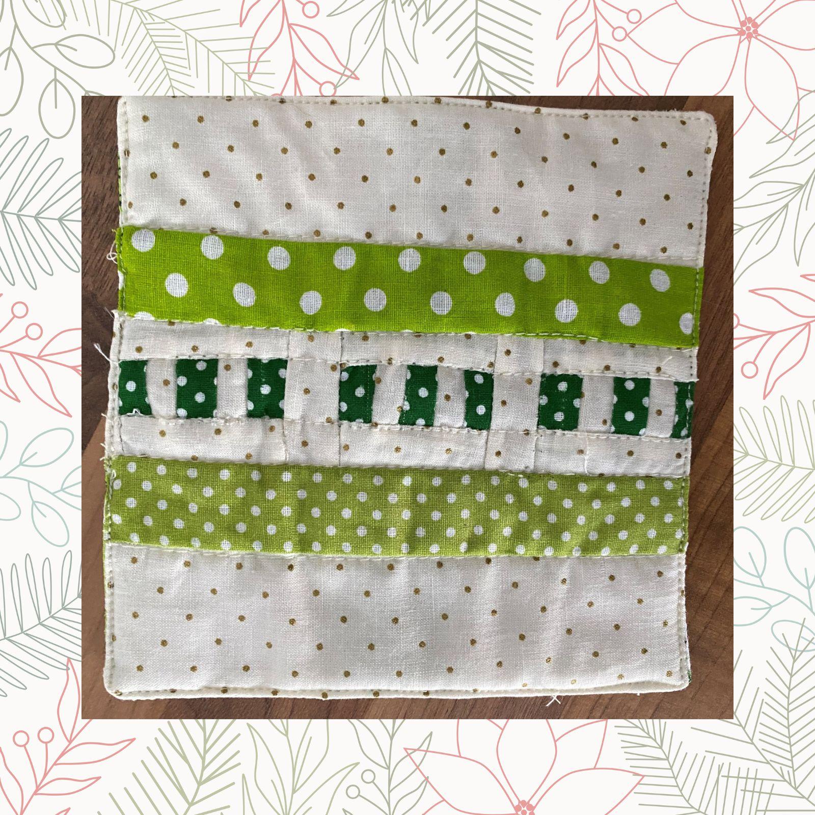 A square quilt with a white background and a green border. The quilt features a pattern of horizontal stripes in green and white, with polka dot and striped patterns within the stripes. The background is quilted with a linear pattern.