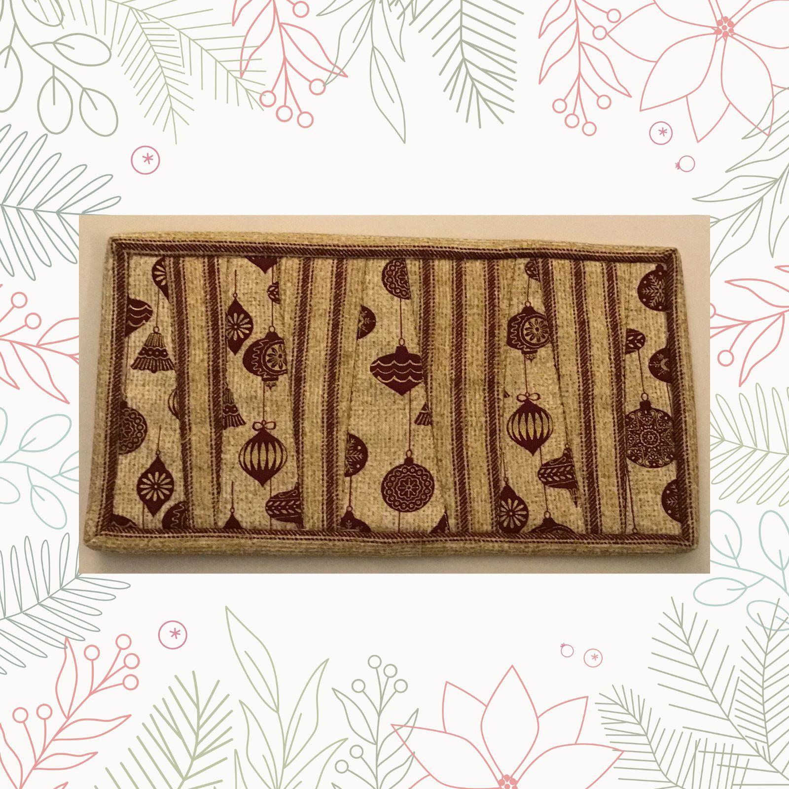 A rectangular quilt with a beige background and a brown border. The quilt features a pattern of hanging ornaments, embroidered in brown thread. The background is quilted with a linear pattern.