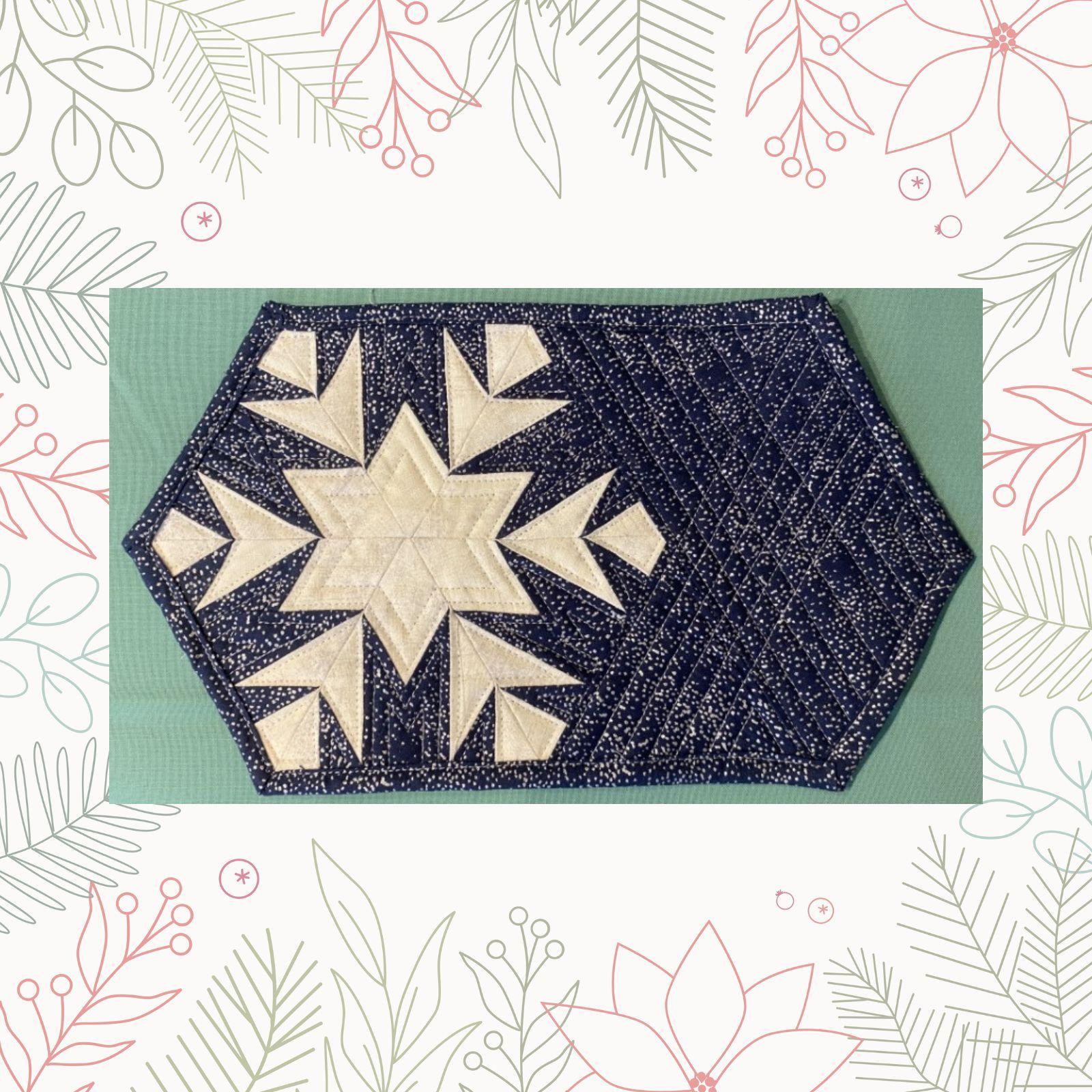 A hexagonal quilt with a dark blue background and a white border. The quilt features a large, white snowflake design in the center. The background is filled with small, white dots, resembling snowflakes.