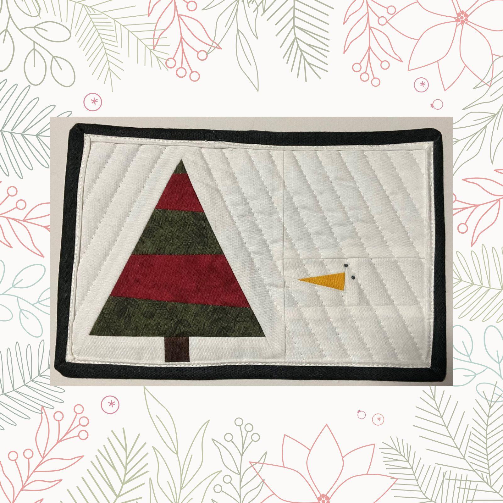 A rectangular quilt with a white background. The quilt features a green Christmas tree with red stripes and a small, white snowman face peeking out from behind. The background is quilted with a linear pattern. The quilt has a black border.