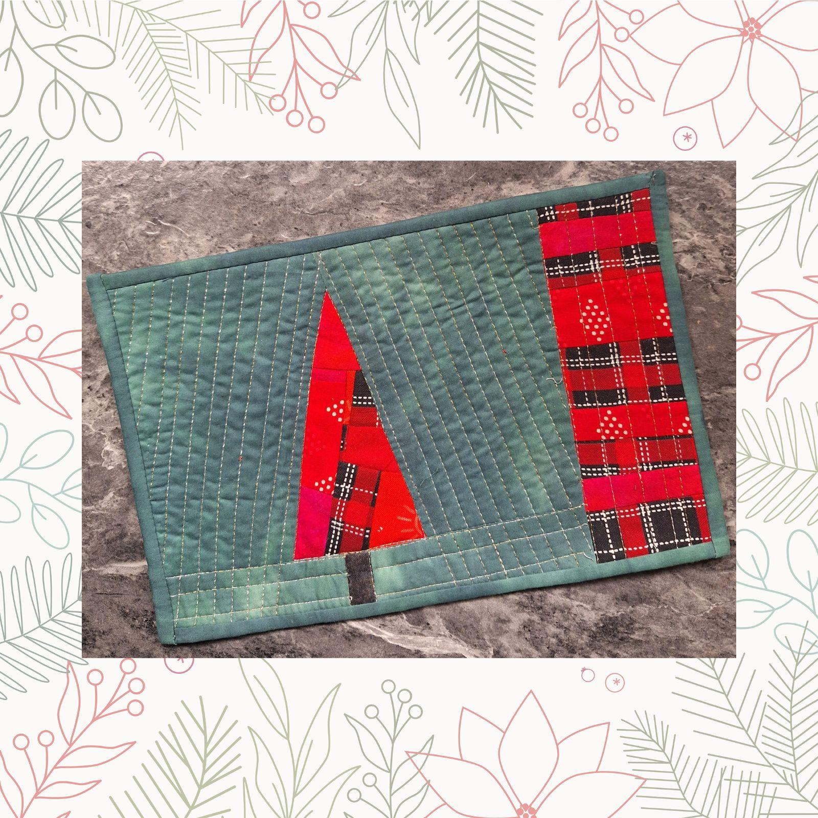 A rectangular quilt with a blue-green background. The quilt features a red and white plaid Christmas tree in the center. The background is quilted with diagonal lines echoing out from the tree.