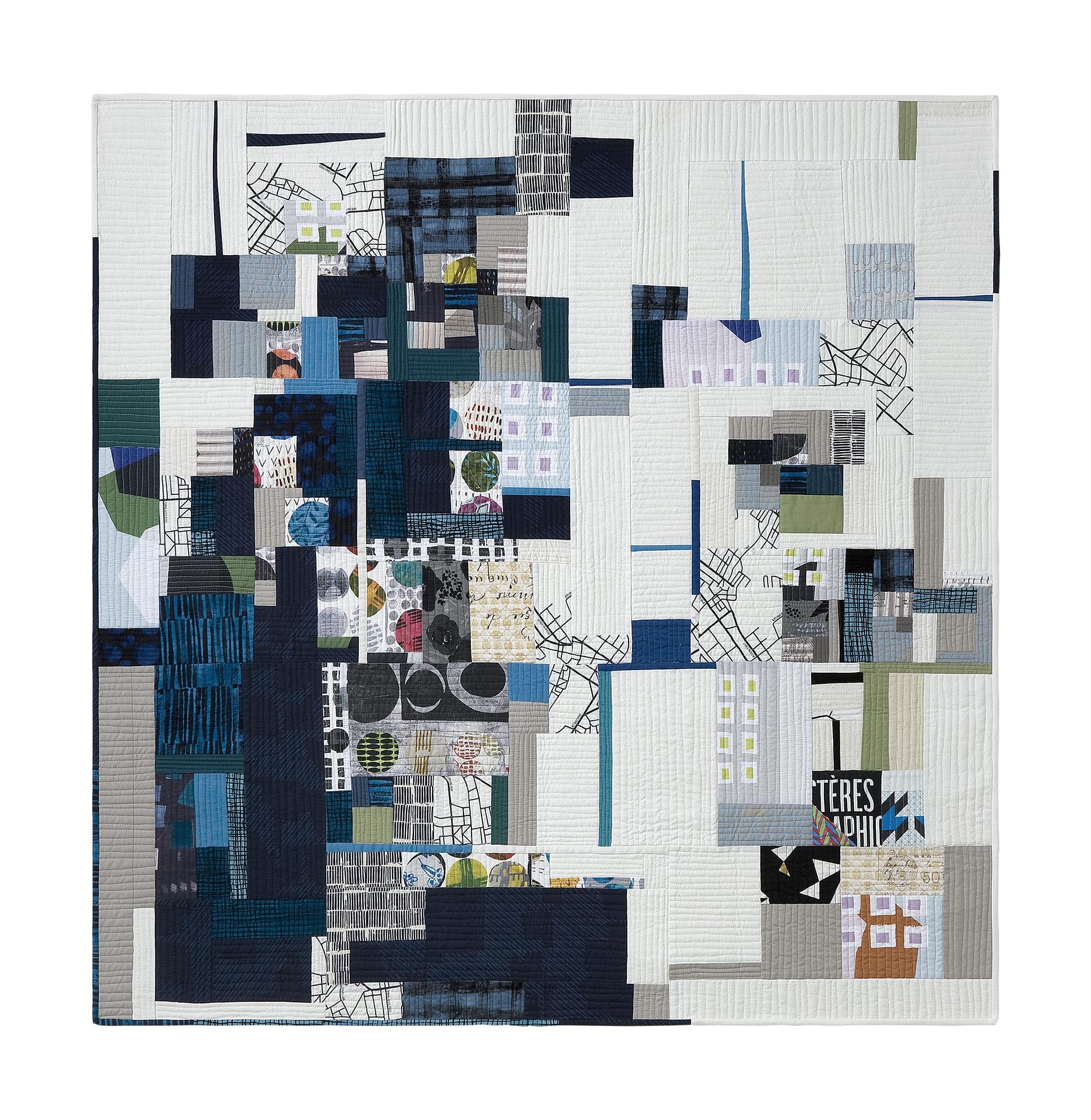 A large, abstract quilt with a predominantly white background. The quilt is composed of various shapes and patterns in shades of blue, gray, and green. There are geometric shapes, organic forms, and textural elements, creating a complex and visually interesting composition. The quilt appears to be made up of numerous smaller pieces of fabric sewn together.