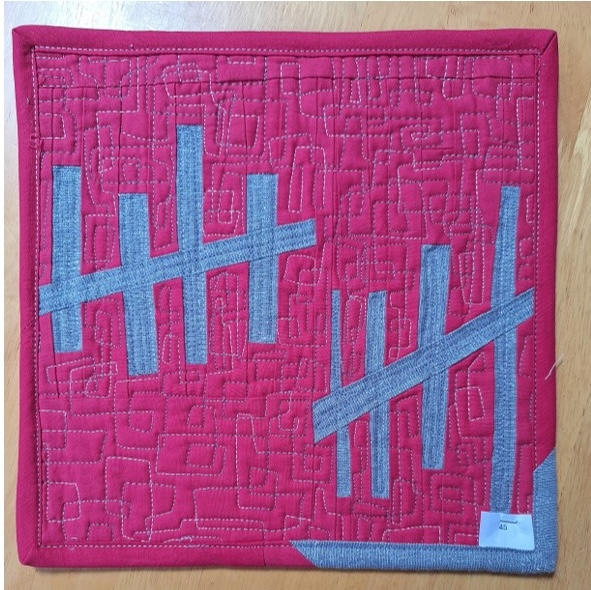A square quilt with a red background and a red border. The quilt features a pattern of gray vertical lines, arranged in groups of five, creating a visual rhythm. The background is quilted with a square meander