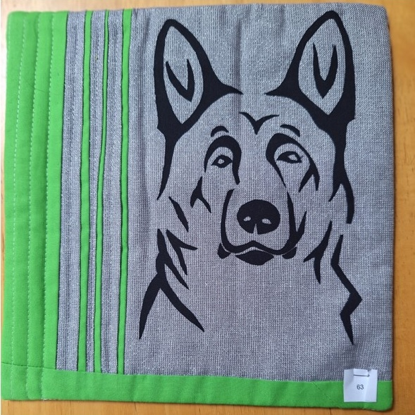 A square quilt with a gray background and a green border. The quilt features a black silhouette of a German Shepherd dog's head.