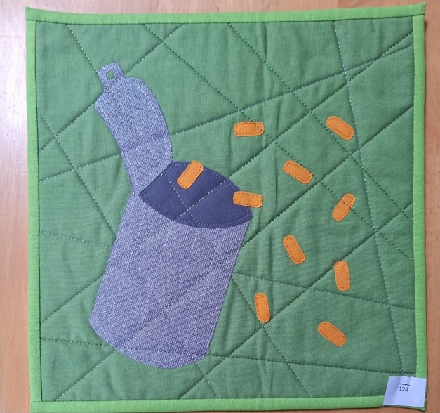 A square quilt with a green background and a green border. The quilt features a gray tin can with orange beans spilling out of it. The background is quilted with a linear pattern.
