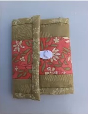 A green and pink quilted needle case with a floral pattern. The case has a white button closure and a green border.