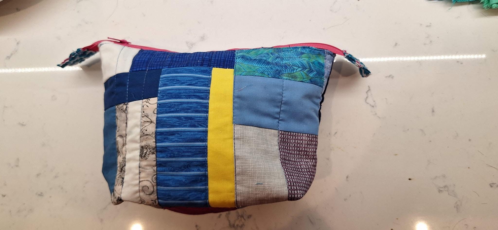 Patchwork zippered pouch in bright modern colours. The pieces are strips of various widths.