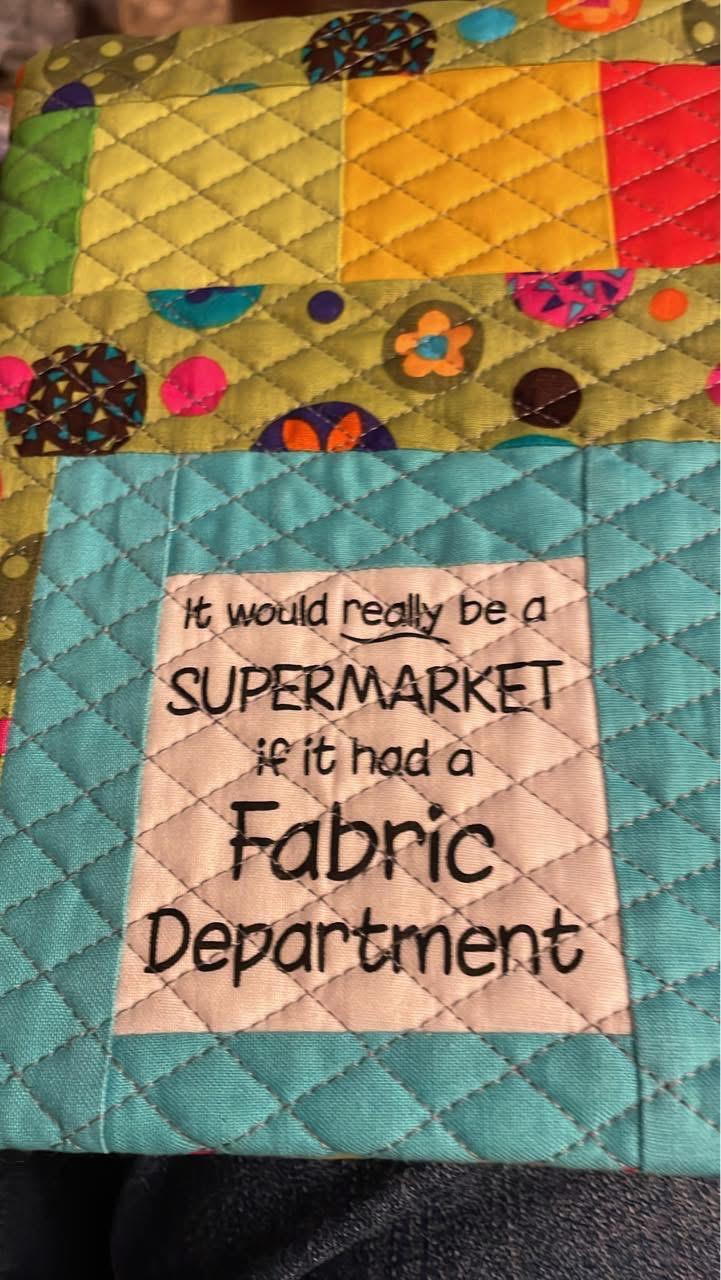 Notebook cover quilted with a diamond crosshatch pattern. The front of the notebook says “it would really be a supermarket if it had a fabric department”