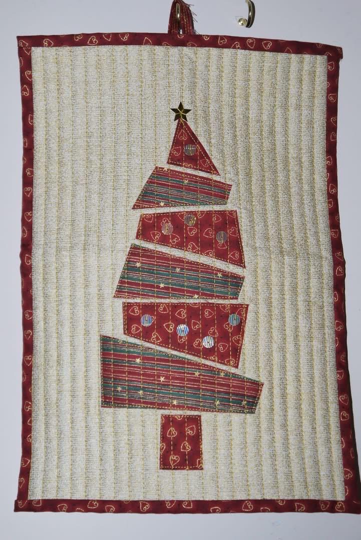 Mini quilt wall hanging of a red patterned Christmas tree on a white background.