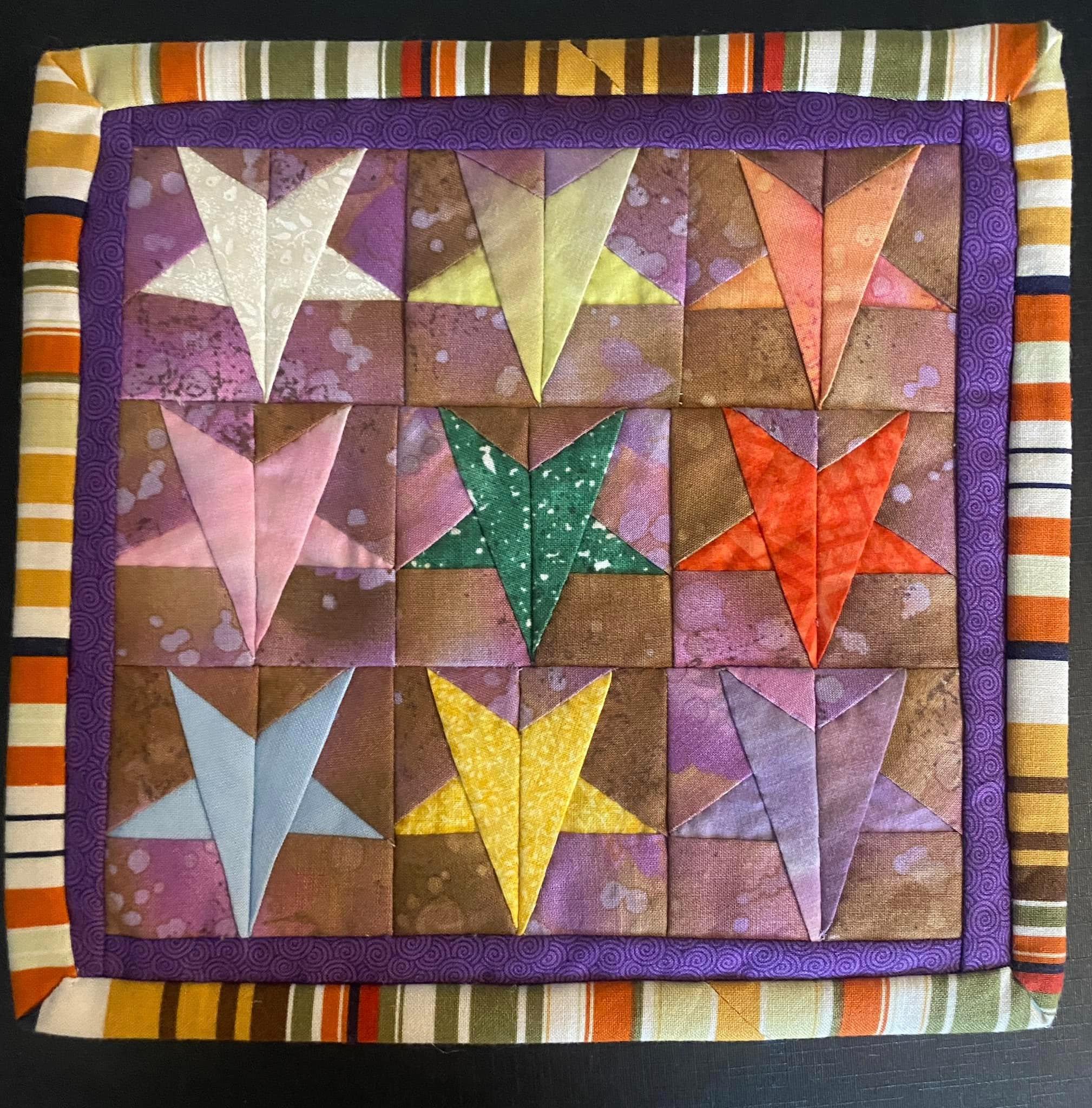 Zippered pouch with a patchwork front and stripy binding.